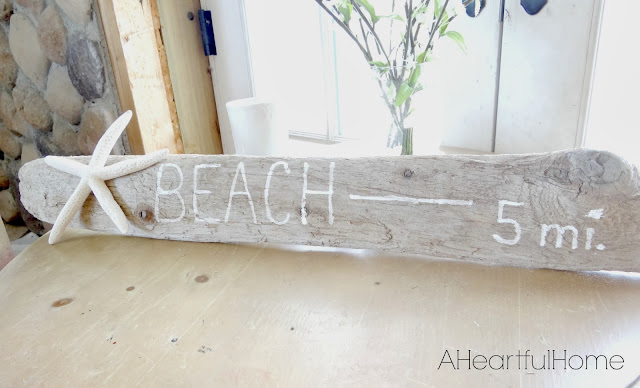 Handpaited driftwood sign that says "beach - 5 miles"